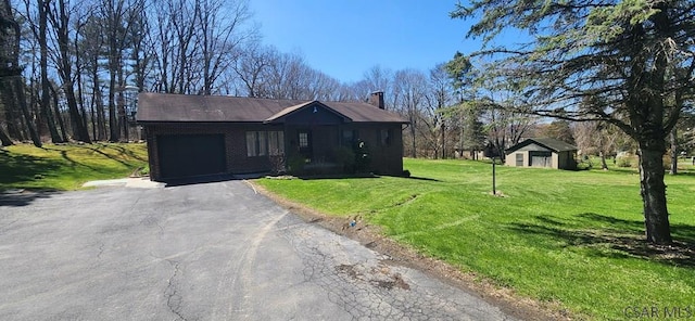 view of front of property with driveway, a chimney, a front yard, a garage, and brick siding