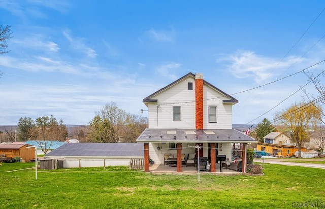 back of property with a patio area, a lawn, and a chimney