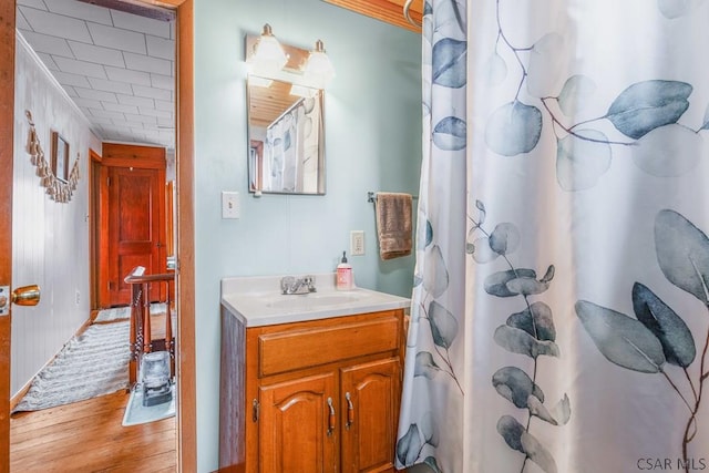 full bathroom with a shower with shower curtain, vanity, and wood finished floors