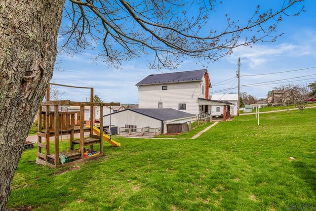 rear view of property with a yard and a playground