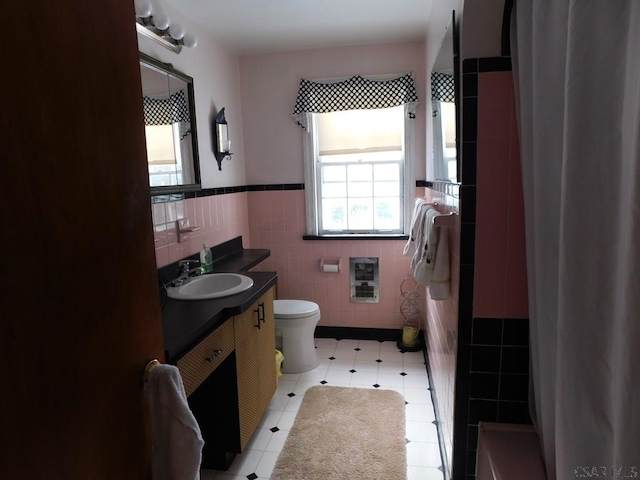 bathroom with heating unit, vanity, toilet, and tile walls