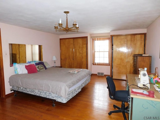 bedroom with hardwood / wood-style flooring and an inviting chandelier