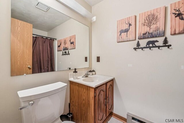 bathroom with a baseboard heating unit, baseboards, vanity, and toilet