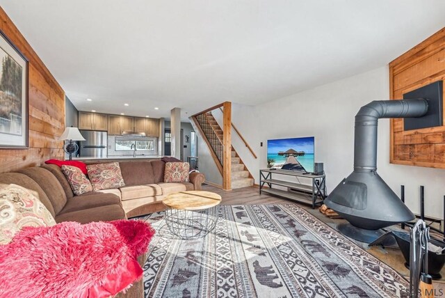 living area with a wood stove, stairway, wood finished floors, and recessed lighting