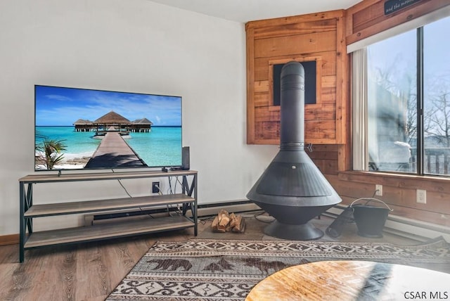 interior space featuring wood finished floors, a wood stove, and baseboards