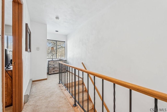 hall with light carpet, a baseboard radiator, baseboards, and an upstairs landing