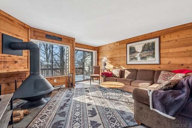 living area with a baseboard heating unit, wood walls, and a wood stove