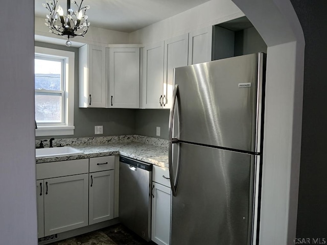 kitchen featuring appliances with stainless steel finishes, light stone countertops, sink, and white cabinets