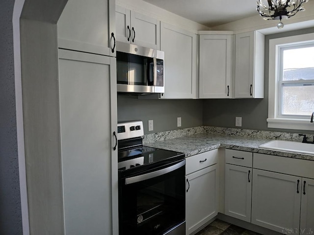 kitchen with appliances with stainless steel finishes, sink, and white cabinets