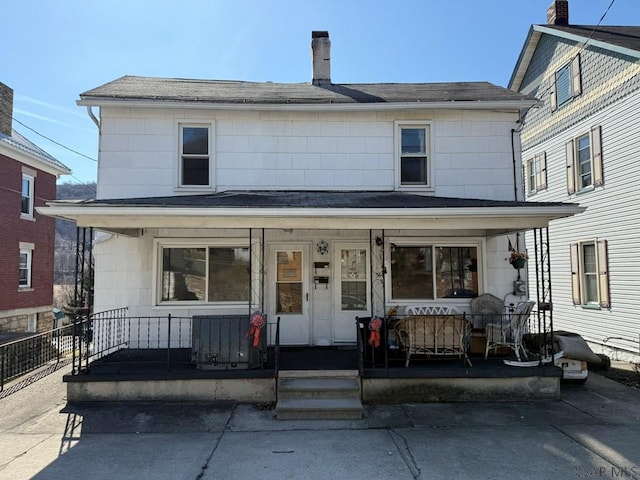 american foursquare style home featuring covered porch and a chimney