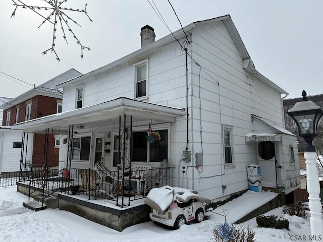 snow covered property with a chimney