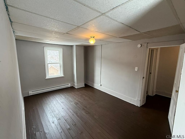 unfurnished room featuring a paneled ceiling, baseboards, a baseboard heating unit, and dark wood-type flooring