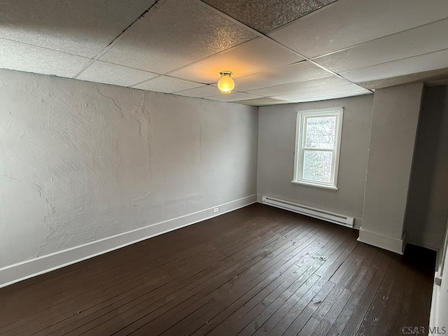 spare room with dark wood-style floors, baseboards, a baseboard heating unit, and a drop ceiling