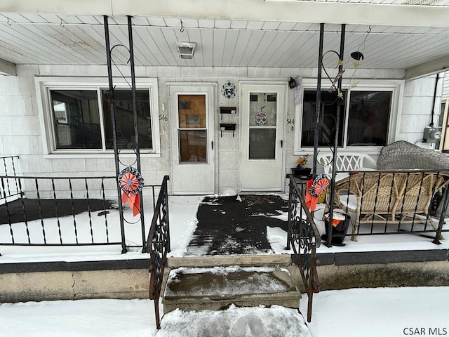 snow covered property entrance featuring a porch