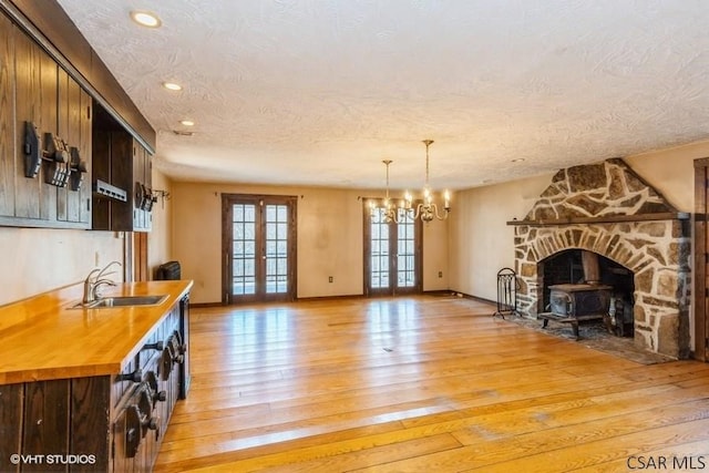 interior space featuring sink, light hardwood / wood-style flooring, an inviting chandelier, a textured ceiling, and french doors