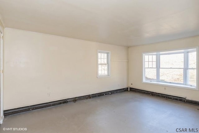 spare room with a baseboard radiator, concrete flooring, and a wealth of natural light