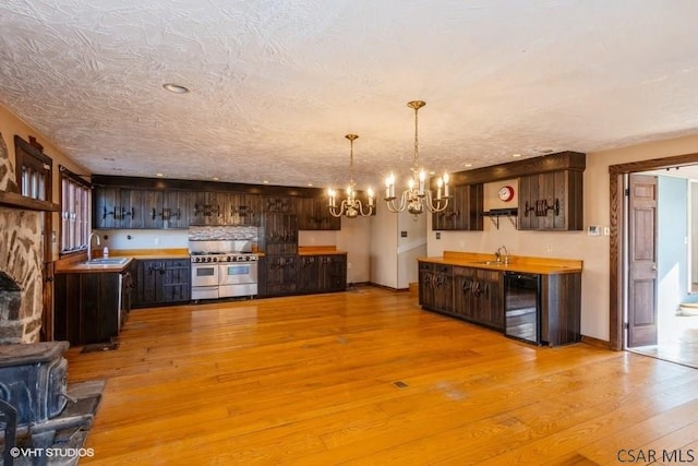 kitchen with dark brown cabinetry, double oven range, beverage cooler, and sink