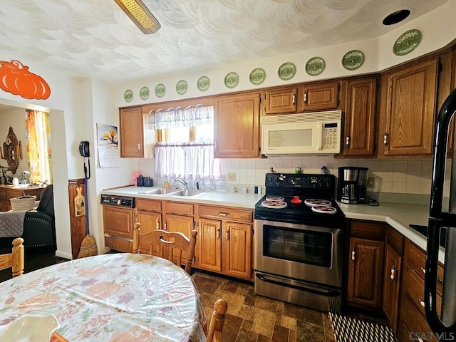 kitchen featuring white microwave, stainless steel electric range oven, a sink, light countertops, and backsplash