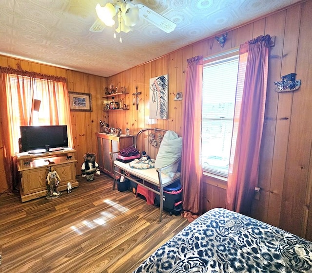 bedroom featuring ceiling fan, wood walls, and wood finished floors