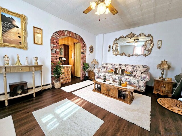 living area with a ceiling fan, arched walkways, and wood finished floors