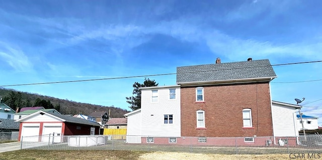 view of side of home with an outbuilding, brick siding, a chimney, and fence