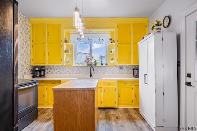 kitchen featuring light countertops, a sink, open shelves, and range with electric stovetop
