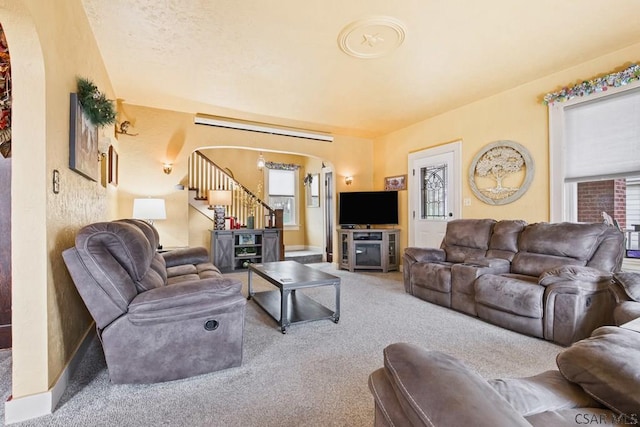 living area featuring stairs, arched walkways, and carpet floors