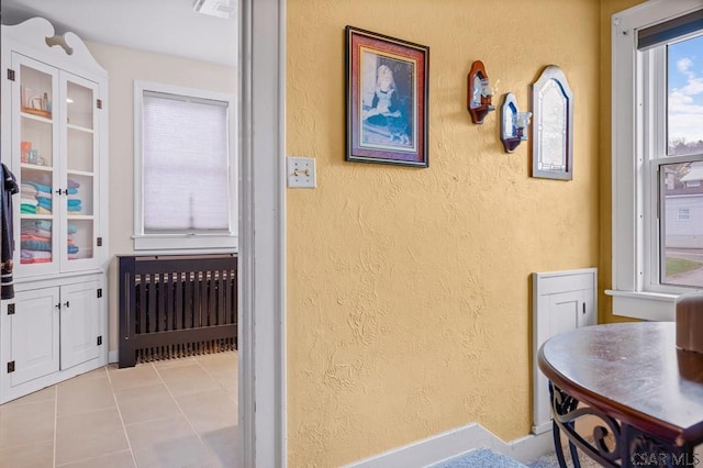 interior space featuring light tile patterned flooring, a textured wall, and visible vents