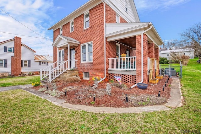 view of front of house with brick siding, a porch, and a front lawn