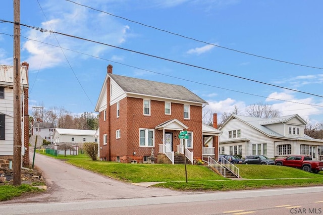 view of front of property with a front lawn, a chimney, and brick siding