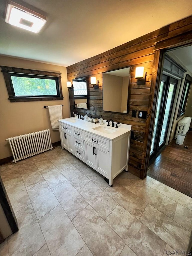 909 Snake Rd, Ebensburg, PA 15931 - bathroom featuring radiator heating unit, wood walls, and double vanity