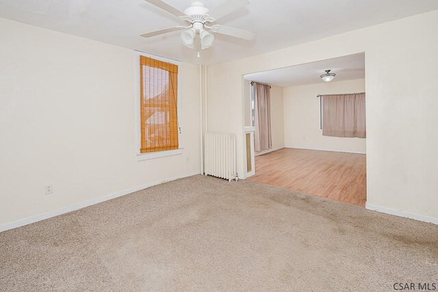 carpeted empty room featuring radiator and ceiling fan