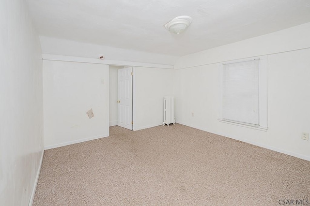 unfurnished room with radiator and carpet floors