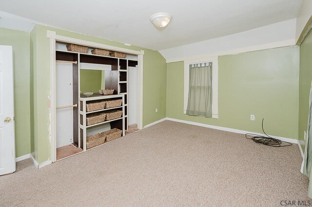 unfurnished bedroom with lofted ceiling, carpet floors, and a closet