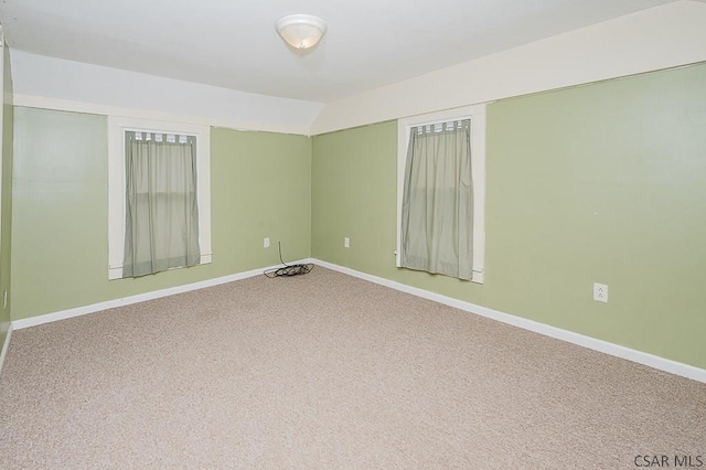 carpeted empty room with lofted ceiling