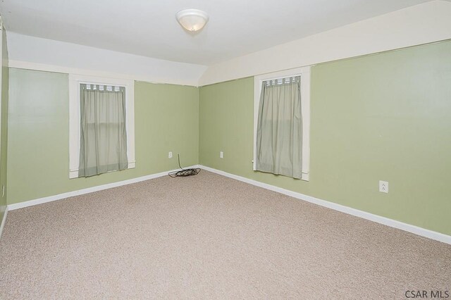 carpeted empty room with lofted ceiling