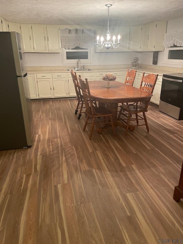 dining room featuring an inviting chandelier, sink, dark wood-type flooring, and a textured ceiling