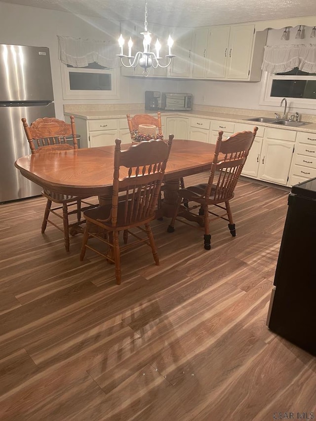 dining room with sink, a chandelier, a textured ceiling, and dark hardwood / wood-style flooring