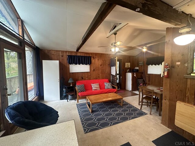 living room with carpet floors, wooden walls, lofted ceiling with beams, and ceiling fan