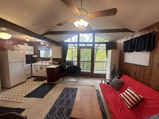 kitchen featuring wood walls, lofted ceiling with beams, white cabinets, ceiling fan, and white appliances