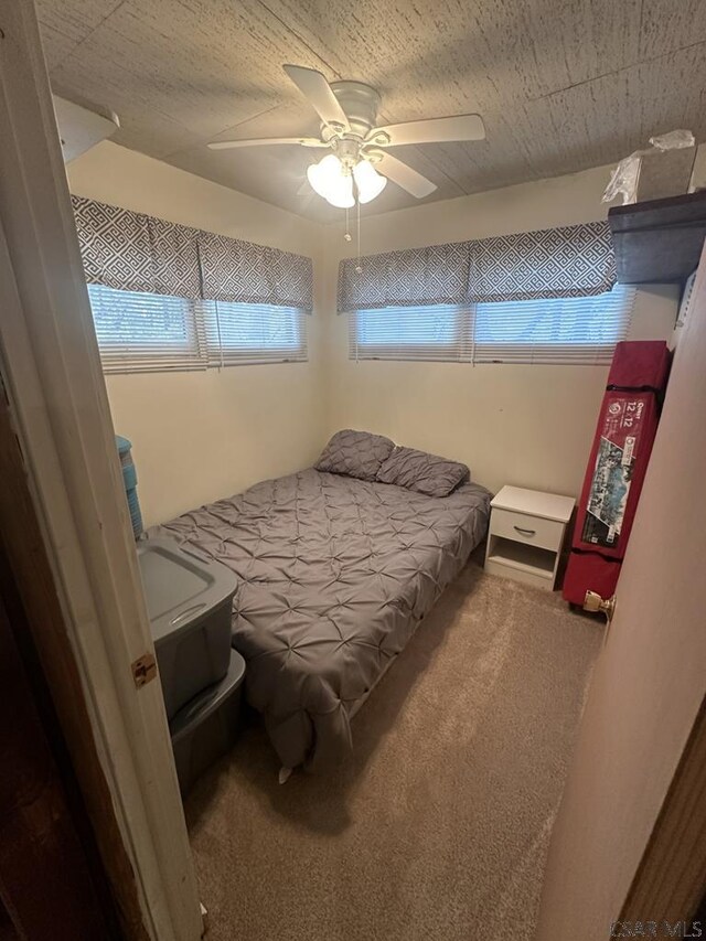 carpeted bedroom with ceiling fan and a textured ceiling