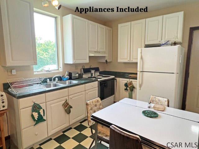 1310 Krayn Rd, Windber, PA 15963 - kitchen featuring white appliances, under cabinet range hood, a sink, dark countertops, and white cabinetry