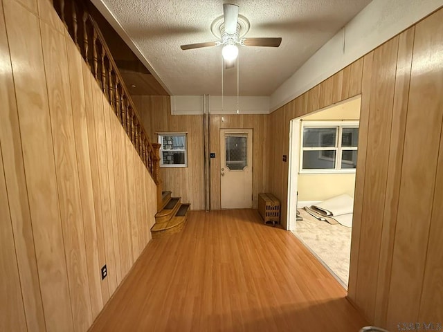 interior space featuring radiator, wooden walls, a textured ceiling, and light wood-type flooring