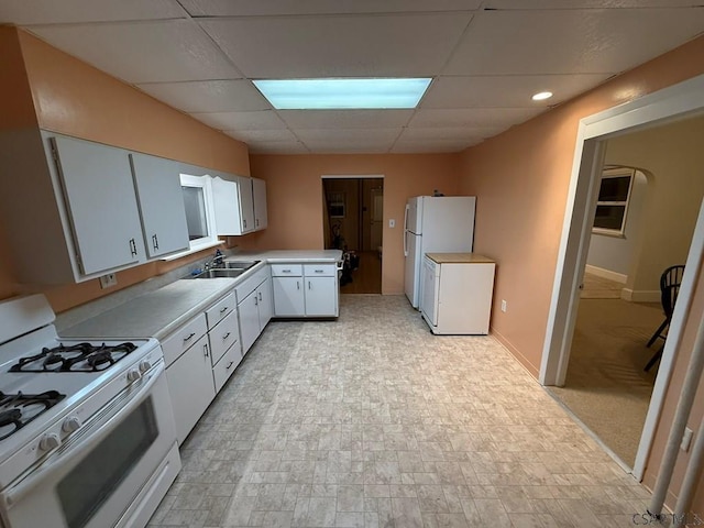 kitchen featuring white appliances, sink, a paneled ceiling, and white cabinets