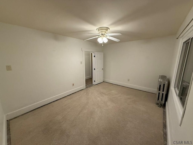 unfurnished bedroom with light carpet, radiator, and ceiling fan