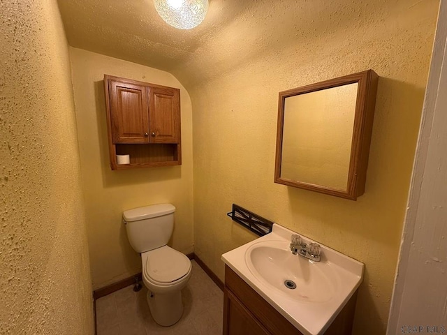 bathroom with tile patterned flooring, vanity, a textured ceiling, vaulted ceiling, and toilet