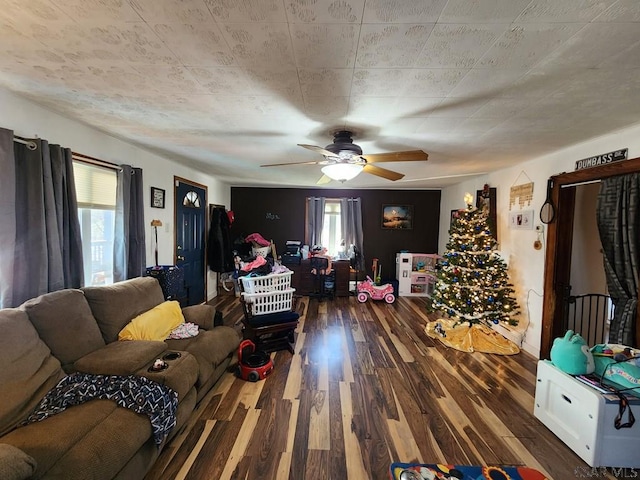 living room with dark wood-type flooring, ceiling fan, and a healthy amount of sunlight