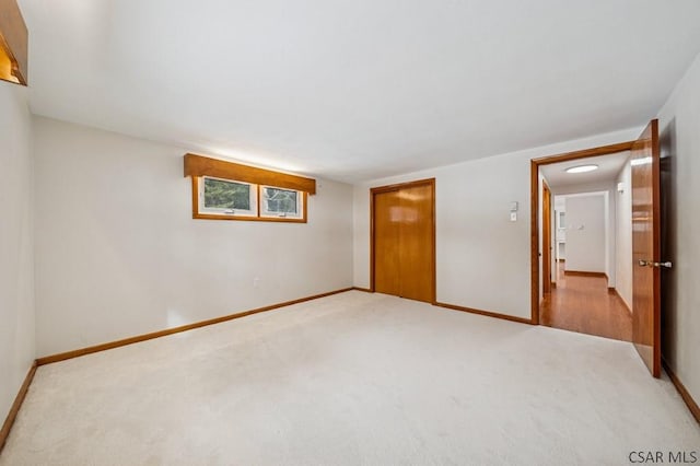 unfurnished bedroom featuring baseboards, a closet, and light colored carpet