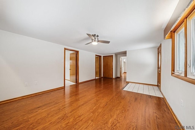 spare room with ceiling fan, light wood-style flooring, and baseboards