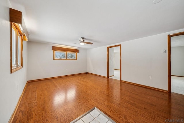 unfurnished room featuring wood finished floors, a ceiling fan, and baseboards